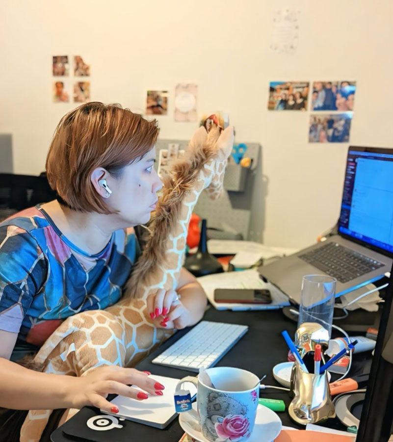 Eleonor working while cuddling a giraffe toy